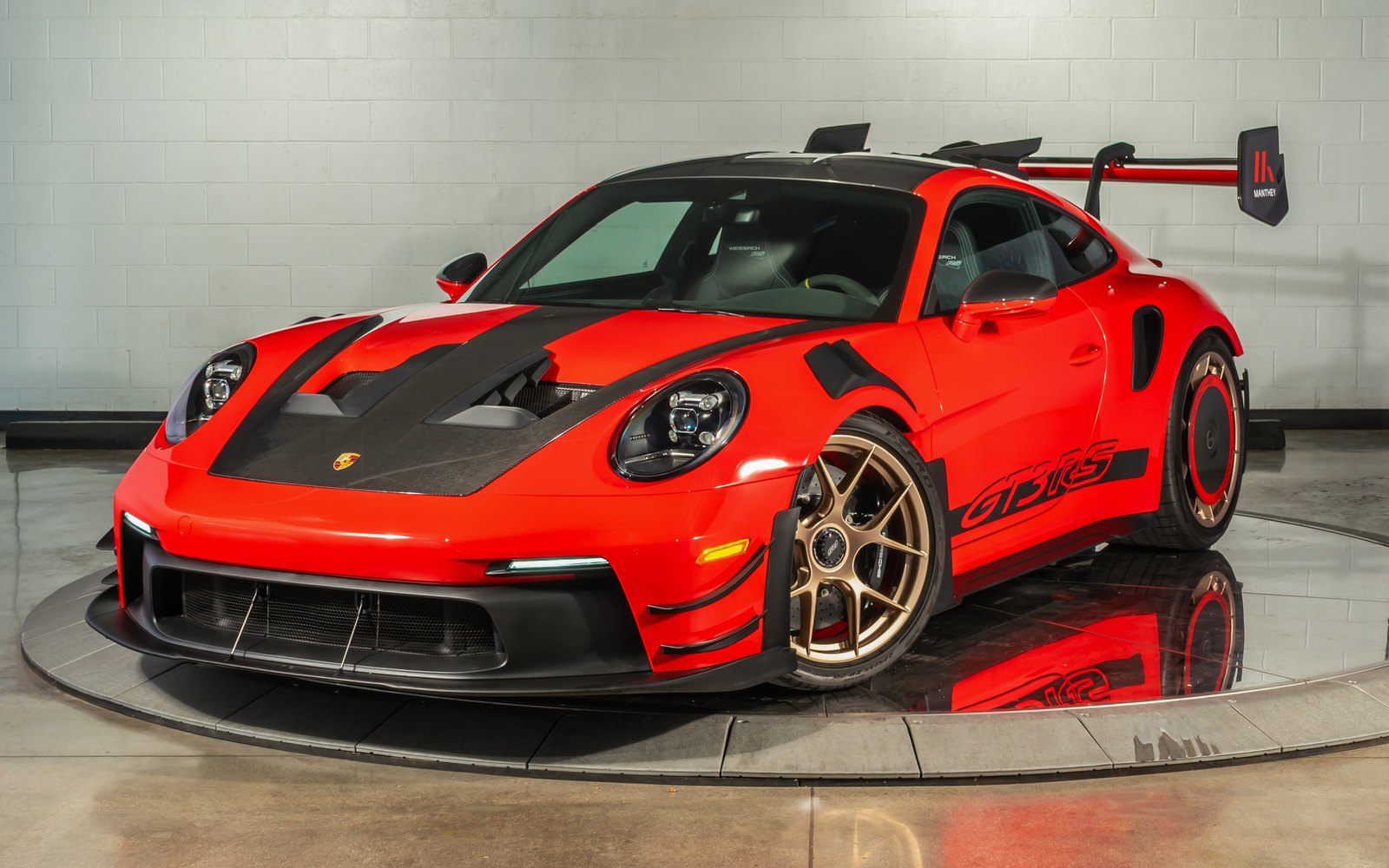 2025 Porsche 911 GT3 RS in Guards Red on an indoor showroom turntable, front three-quarter view