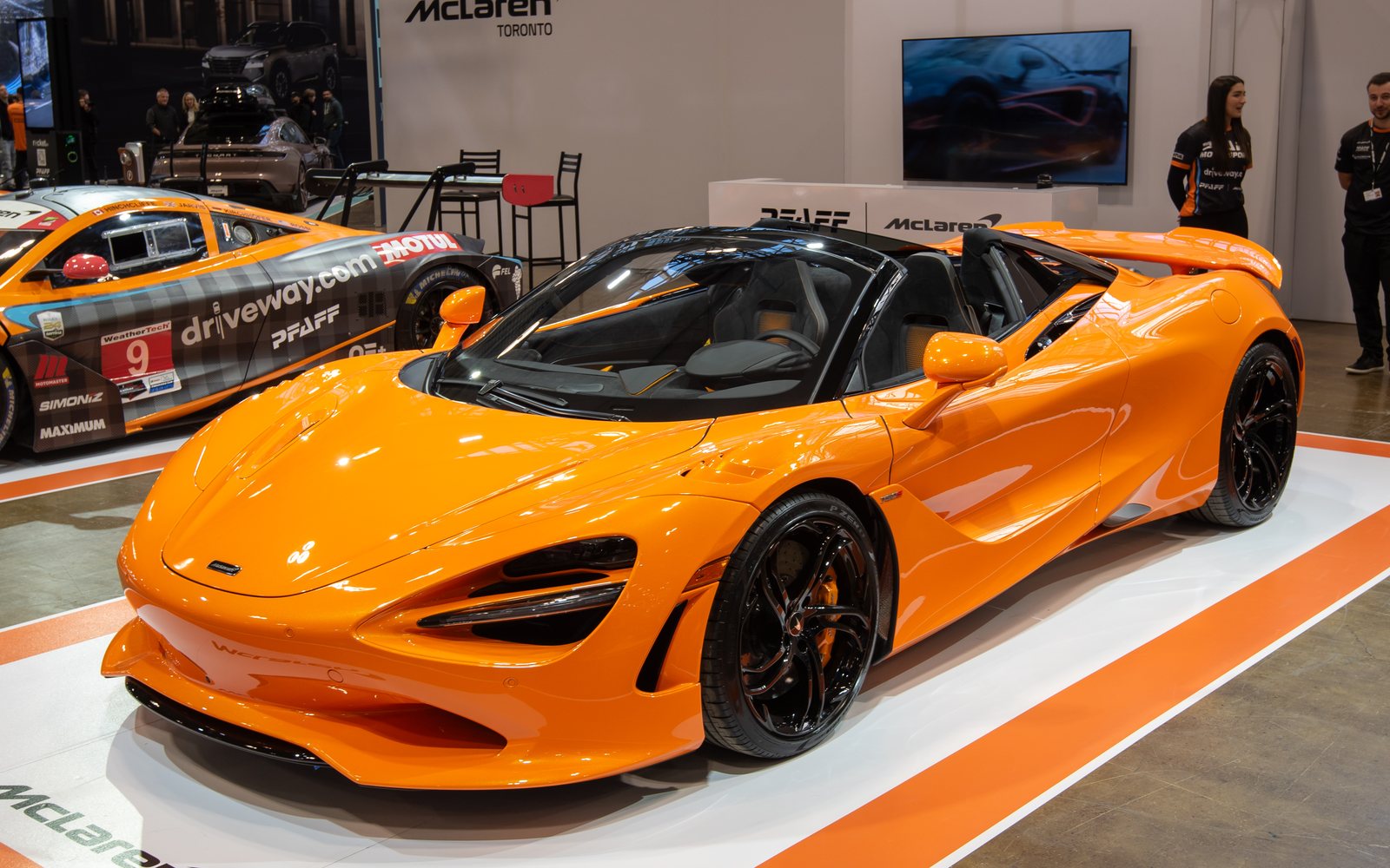 McLaren 750S Spider in bright orange on an indoor McLaren display stand, front three-quarter view